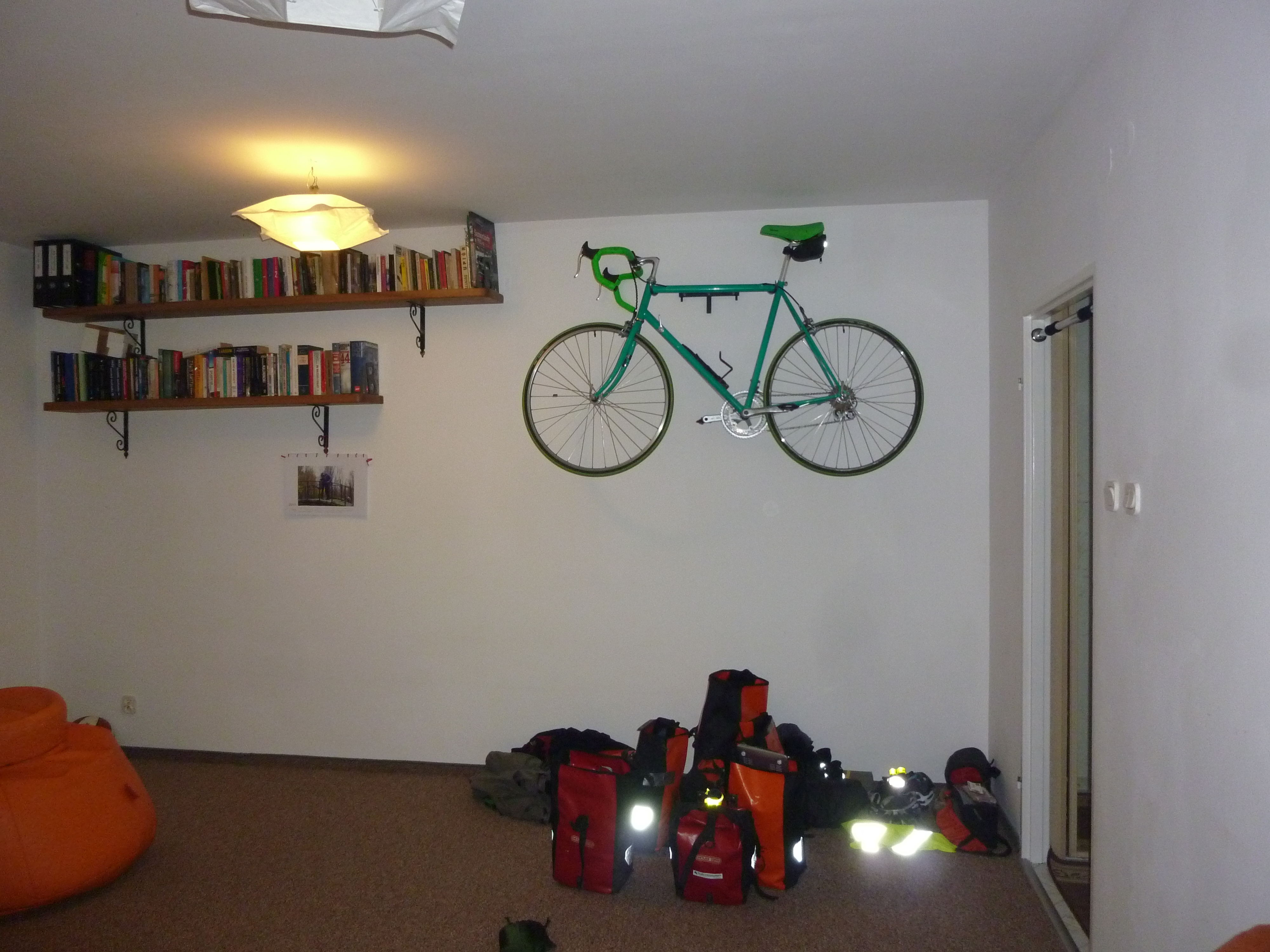 A true cyclist home with a bike on the wall and panniers on the floor.